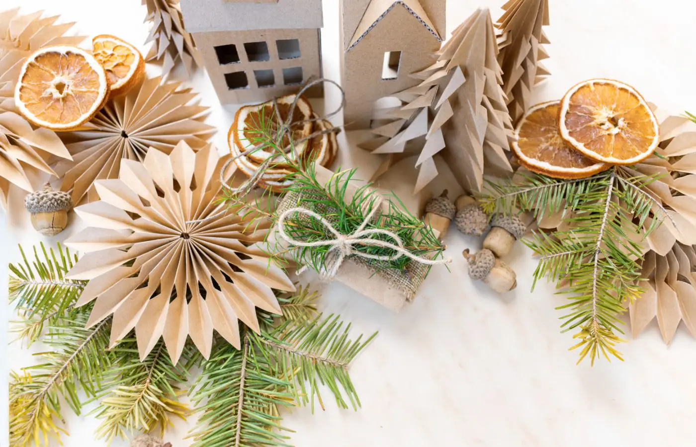 Décorations de Noël écoresponsables avec des ornements en papier recyclé, des branches de sapin et des tranches d’agrumes séchées.